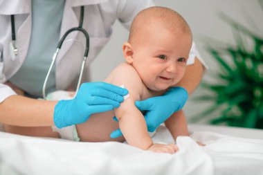 Korkmuş bebek koluna iğne yapmaya hazırlanıyor.