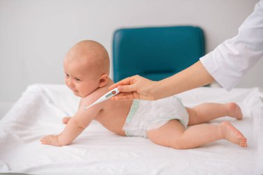 Çocuk doktoru ateşini ölçmeye hazırlanıyor.