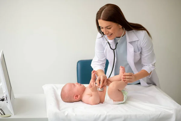 Focado médico feminino auscultando um bebê bonito chorando — Fotografia de Stock