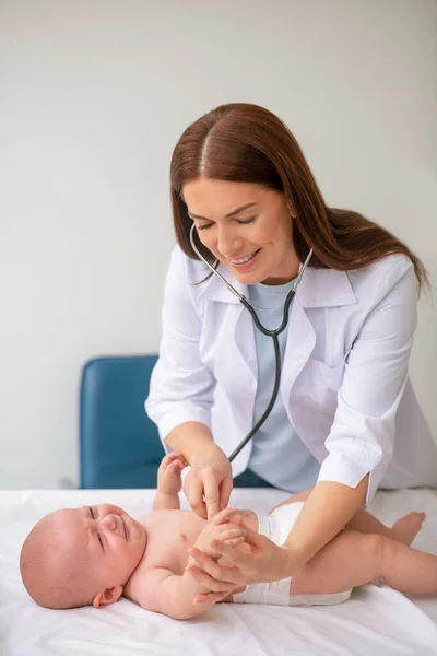 Erfahrene Kinderärztin, die das Herz des neugeborenen Patienten auskultiviert — Stockfoto