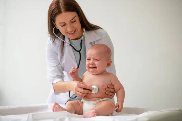 Pediatra amigable escuchando el latido del corazón del bebé usando un estetoscopio —  Fotos de Stock