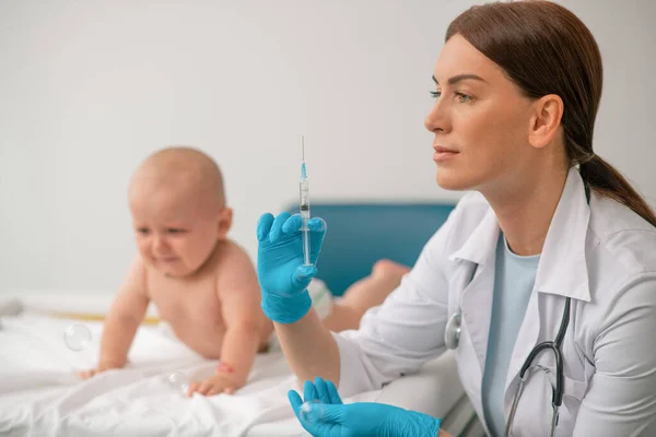 Médico que se prepara para administrar uma injeção a um recém-nascido — Fotografia de Stock