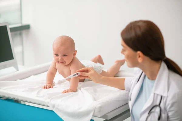 Profissional de saúde experiente se preparando para tomar uma temperatura recém-nascido — Fotografia de Stock