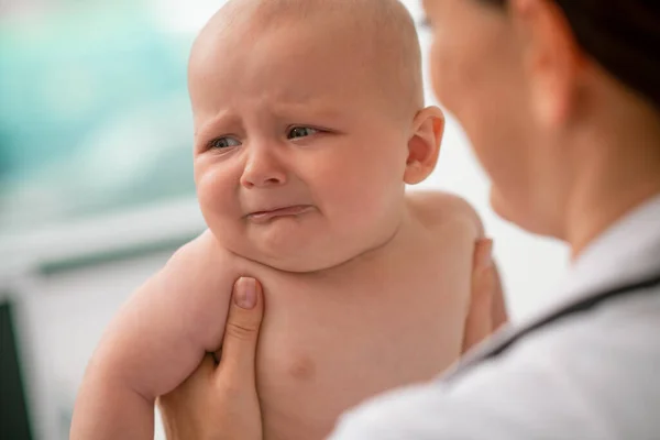Испуганный новорожденный смотрит в сторону во время медицинского осмотра — стоковое фото