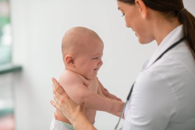 Yeni doğmuş bir bebeği muayene eden deneyimli bir çocuk doktoru.