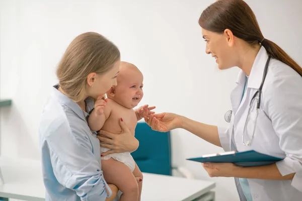 어린 어머니가 아기와 함께 소아과 의사를 방문하는 모습 — 스톡 사진