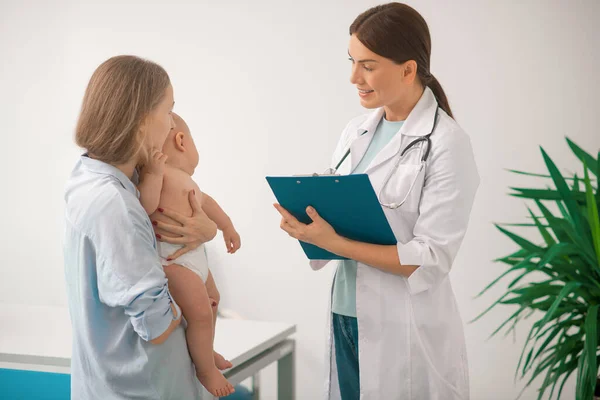 Junge Mutter besucht Kinderarzt mit ihrem kleinen Baby — Stockfoto