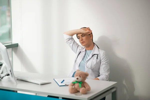 Um médico sentado à mesa e sentindo-se cansado — Fotografia de Stock