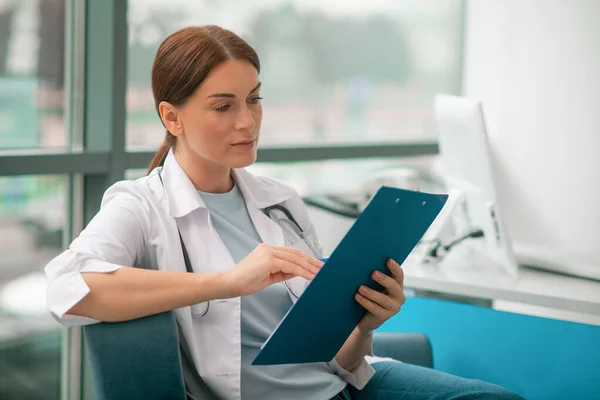 Una doctora guapa con túnica blanca que se ve pensativa — Foto de Stock