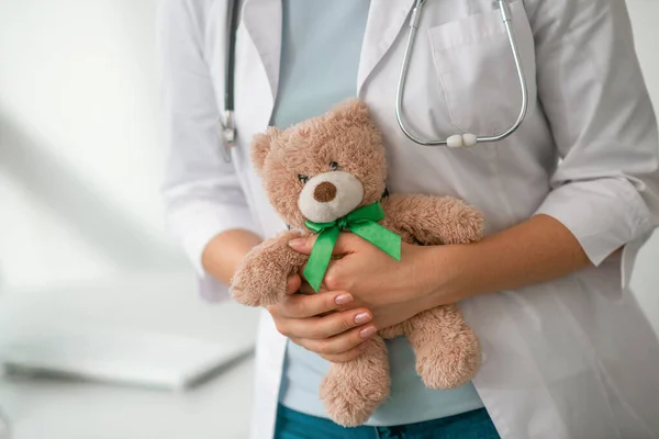 Uma imagem de perto de médico feminino segurando um ursinho de pelúcia nas mãos — Fotografia de Stock