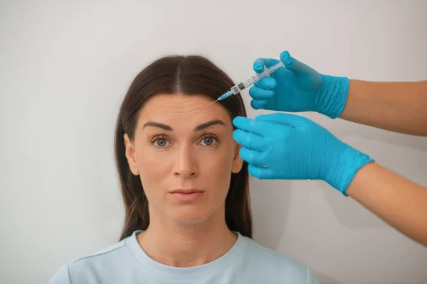 Una mujer de cabello oscuro de mediana edad que se somete a un procedimiento de inyecciones beaty —  Fotos de Stock