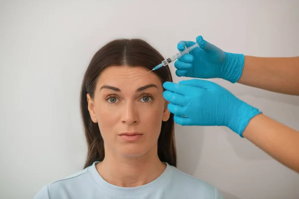 Eine dunkelhaarige Frau mittleren Alters, die eine schöne Spritze bekommt — Stockfoto