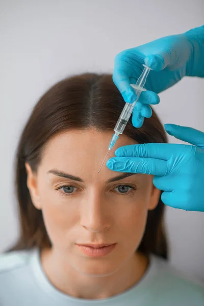 Eine dunkelhaarige Frau mittleren Alters, die eine schöne Spritze bekommt — Stockfoto