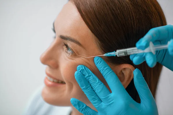 Une femme d'âge moyen aux cheveux bruns ayant une procédure d'injection battante — Photo