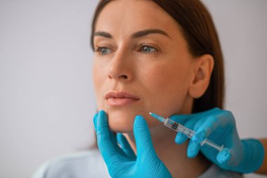 Koyu renk saçlı bir kadın Cometology 'de güzellik tedavi prosedürleri uyguluyor.