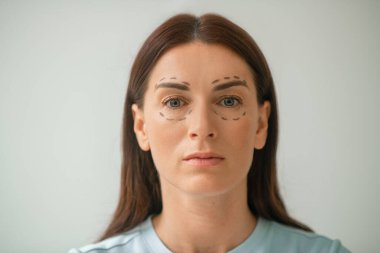 Yüzünde çizgiler olan koyu renk saçlı bir kadının resmi.