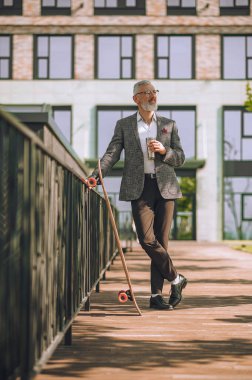 Olgun bir adam ofcy binasının yanındaki avluda duruyor.