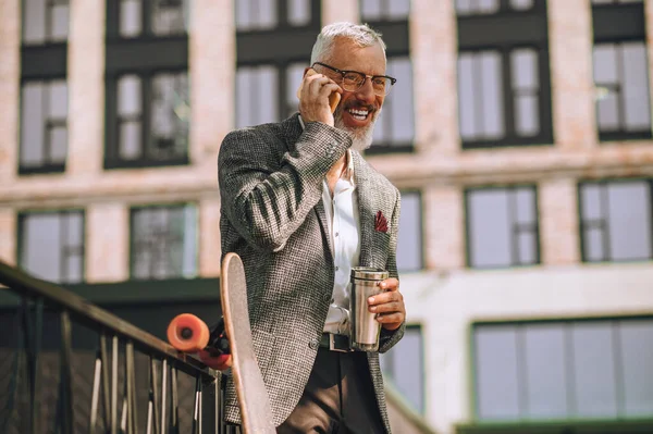 En gråhårig man med en pryl i händerna — Stockfoto