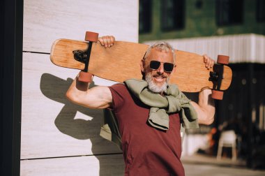 Kameraya gülümseyen neşeli olgun kaykaycı.