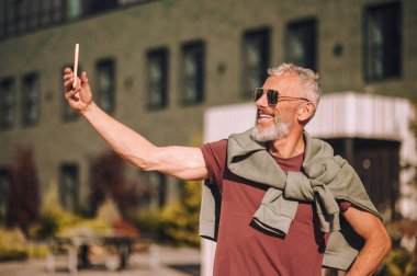 Neşeli adam kendini akıllı telefonuyla fotoğraflıyor.