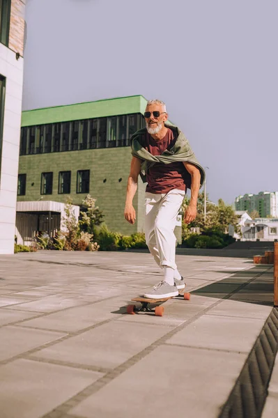 Седовласый бородатый скейтбордист на улице — стоковое фото