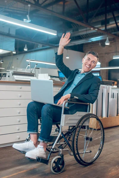 Άνδρας σε αναπηρική καρέκλα καλοδεχούμενος σηκώνοντας το χέρι στο γραφείο — Φωτογραφία Αρχείου