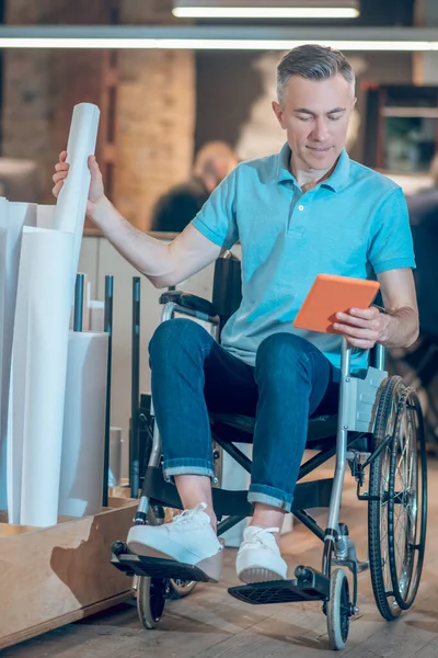 Άνδρας σε αναπηρικό αμαξίδιο με χάρτινο ρολό συγκράτησης δισκίων — Φωτογραφία Αρχείου