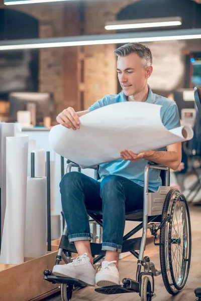 Чоловік у інвалідному візку дивиться ескіз із задоволенням — стокове фото