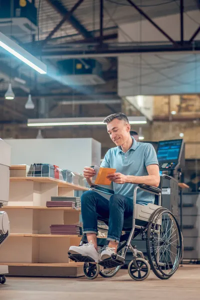 Άντρας σε αναπηρικό καροτσάκι βγάζει καρτ ποστάλ από το φάκελο — Φωτογραφία Αρχείου
