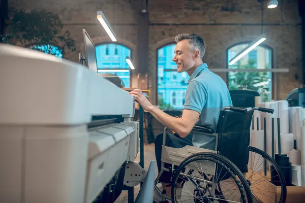 Perfil do homem em cadeira de rodas tocando impressora — Fotografia de Stock