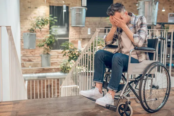 Άνδρας σε αναπηρική καρέκλα καλύπτει το πρόσωπο με τα χέρια του — Φωτογραφία Αρχείου