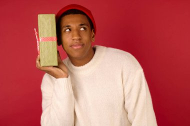 Elinde hediye kutusu olan esmer tenli genç bir adam.