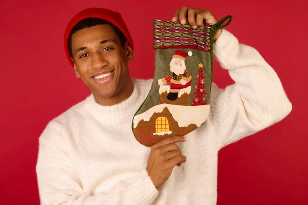 Un joven de piel oscura con una media de Navidad en las manos — Foto de Stock