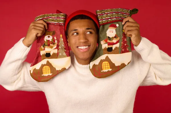 Un joven de piel oscura sosteniendo medias de Navidad — Foto de Stock