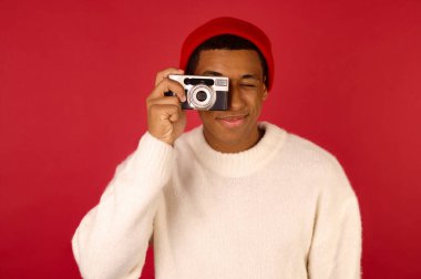 Elinde kamera olan, Noel Baba şapkalı bir adam.