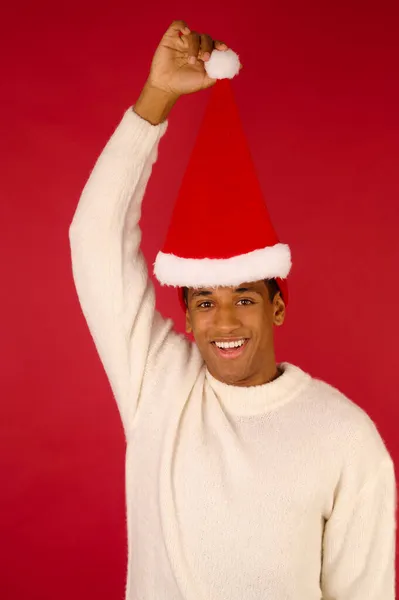 Jovem sorrindo cara com santa chapéu com na mão — Fotografia de Stock