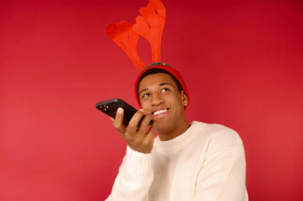 Un hombre de piel oscura con sombrero con cuernos y un teléfono en las manos — Foto de Stock