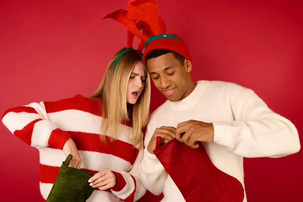 Mladí lidé v kloboucích s parohy kontrolu jejich vánoční punčochy — Stock fotografie
