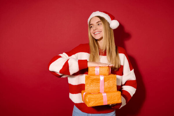 Девушка в полосатом свитере держит много подарочных коробок