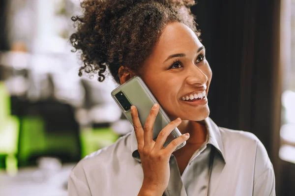 Roztomilá usměvavá žena s tmavou pletí mluví po telefonu — Stock fotografie