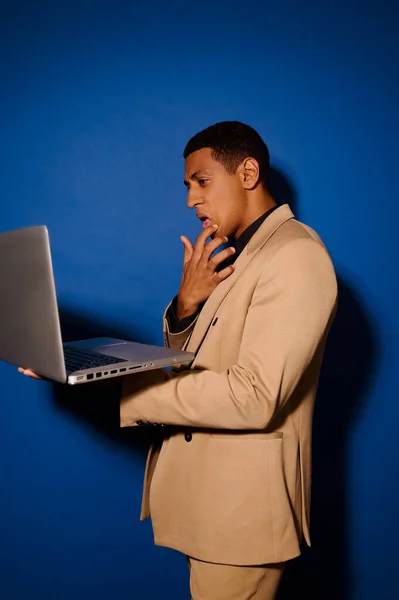 Guy standing sideways to camera looking at laptop — Stock Photo, Image