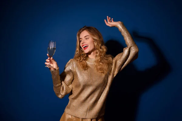 Menina alegre olhando para o copo de champanhe na mão — Fotografia de Stock