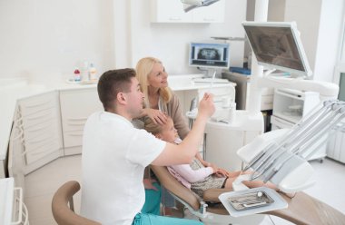 Bir erkek doktor, röntgen sonuçlarını çocuklara veriyor, anne.