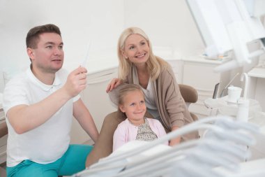 Çocukların annelerine röntgen sonuçlarını gösteren bir erkek doktor.