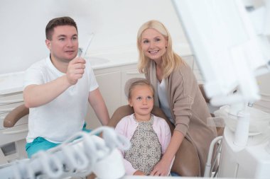 Çocukların annelerine röntgen sonuçlarını gösteren bir erkek doktor.