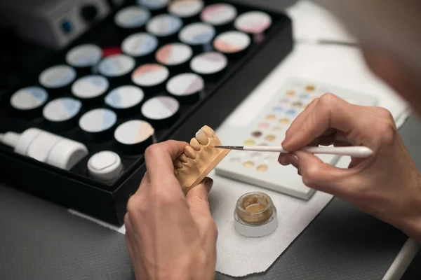 A dental prosthetist painting a prosthesis with a brush — Foto Stock