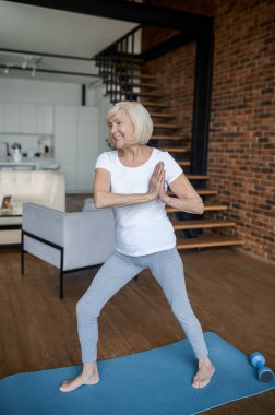 Zayıf yaşlı kadın evde yoga yapıyor.