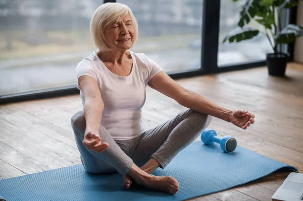 Senior woman sitting on the floor ain a lotus pose — Stockfoto