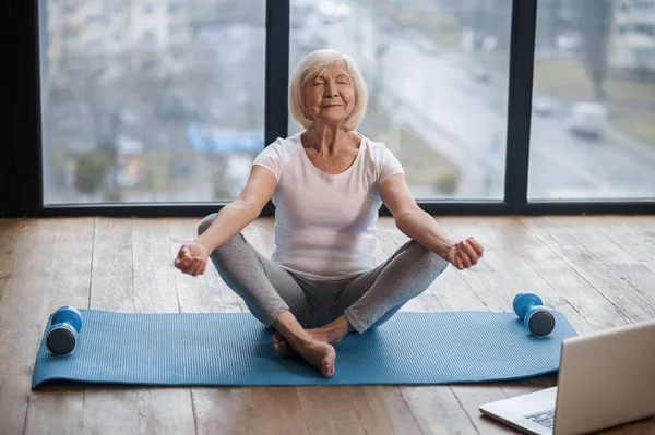 Senior woman sitting on the floor ain a lotus pose — 스톡 사진