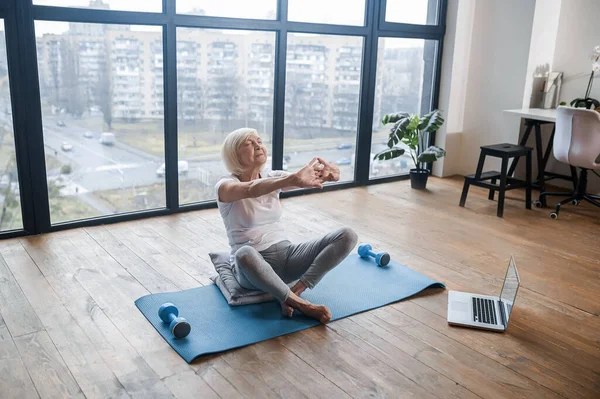 Gray-haired senior woman in sportswear doing stretching — Stockfoto